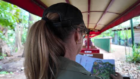 Women-riding-on-a-sightseeing-adventure-train-reading-a-map-while-traveling-through-a-tropical-location