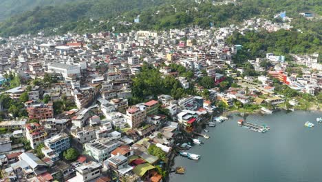 Drone-descends-to-Lake-Atitlan-Guatemala-showcasing-city-suburb-homes-and-buildings