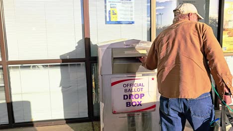 Baby-Boomer-Generation-Man-Votes-by-Droping-Mail-in-Ballot-Letter-in-Slot-at-Voting-Booth-with-Offical-Ballot-Drop-Box-Sign-for-Democratic-Government-Election-in-Presidential-Race