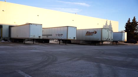 4K-Gimbal-Daytime-Morning-Establishing-Shot-Back-Lot-Warehouse-Distribution-Center-Loading-Bay-with-Bison-Semi-Tricks-Long-Haul-Delivery-Transportation-Supply-Chain-Vehicles