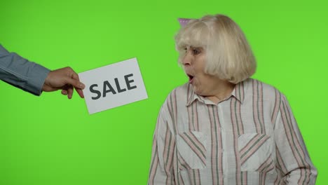 Inscription-advertising-Sale-word-appears-next-to-joyful-grandmother-with-shopping-bags.-Chroma-key