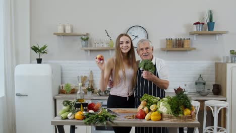 Mature-man-with-grandchild-girl-recommending-eating-raw-vegetable-food.-World-vegan-day-concept