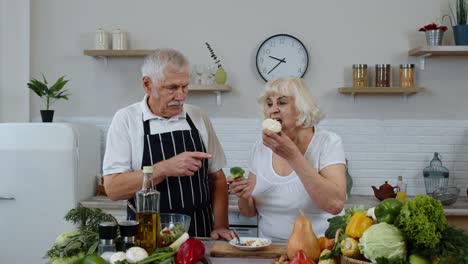 Senior-couple-in-kitchen.-Elderly-grandmother-and-grandfather-eating-raw-broccoli-and-cauliflower