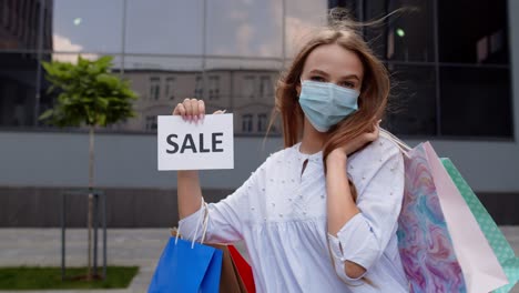 Mädchen-In-Schutzmaske-Mit-Einkaufstüten,-Die-Während-Der-Covid-19-Pandemie-Die-Aufschrift-„Sale“-Zeigen