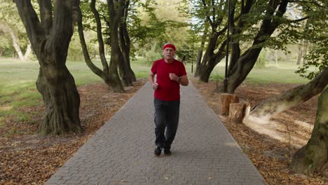 Anciano-Corriendo,-Haciendo-Ejercicio-Cardiovascular-En-El-Parque-Y-Usando-Auriculares-Bluetooth,-Escuchando-Música