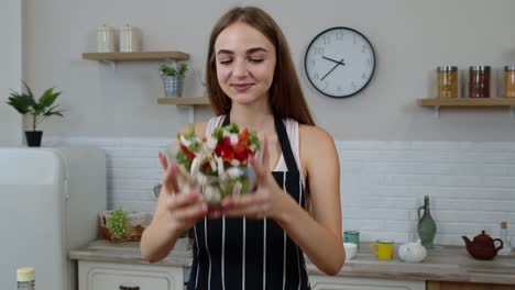 Happy-young-woman-eating-fresh-raw-vegetable-salad-posing-at-kitchen-having-positive-emotion