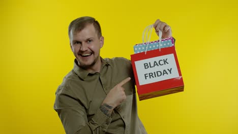Mann-Zeigt-Die-Aufschrift-„Black-Friday“-Auf-Einkaufstüten,-Lächelt,-Zufrieden-Mit-Einkäufen-Zu-Niedrigen-Preisen