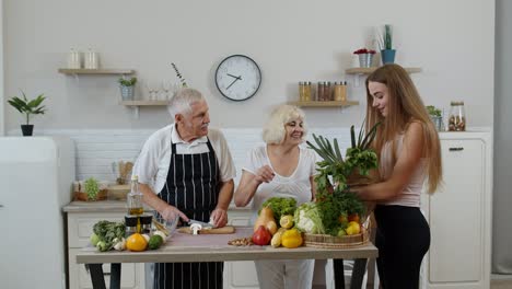 Elderly-couple-in-kitchen-receiving-vegetables-from-grandchild.-Raw-food-healthy-eating-diet