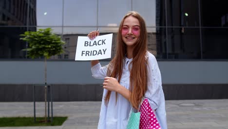 Cheerful-girl-showing-Black-Friday-inscription-text-advertisement.-Online-shopping-with-low-prices
