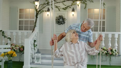 Senior-couple-together-in-front-yard-at-home.-Man-swinging-woman-during-Coronavirus-quarantine