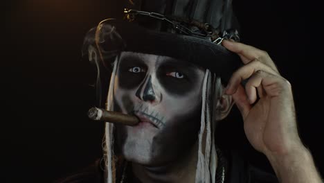 Sinister-man-with-horrible-Halloween-holiday-skeleton-makeup-raising-his-head-and-smoking-cigar