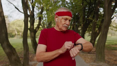Senior-runner-man-in-park-using-smart-watch,-tracking-distance,-checking-pulse-after-fitness-workout