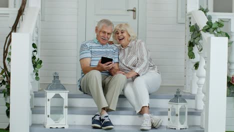 Älteres-Paar-Nutzt-Digitales-Tablet-Auf-Der-Veranda-Zu-Hause.-Ansehen-Lustiger-Videos-Im-Social-Media-Netzwerk