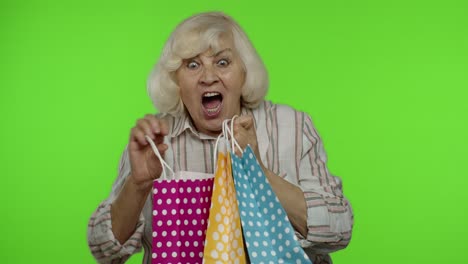 Ältere-Großmutter-Zeigt-Lächelnd-Die-Aufschrift-„Black-Friday“-Aus-Der-Einkaufstasche-Und-Freut-Sich-über-Rabatte