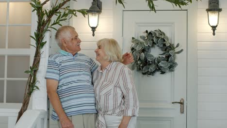 Senior-couple-husband-and-wife-embracing,-showing-love-each-to-other-in-porch-at-home.-Mature-family