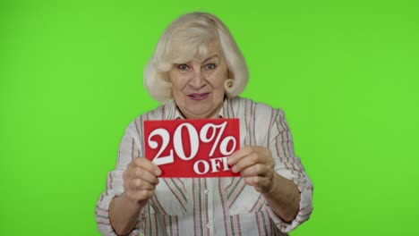 Lächelnde-Großmutter-Zeigt-20-Prozent-Rabatt-Auf-Aufschriftsschildern-Und-Freut-Sich-über-Gute-Rabatte-Und-Niedrige-Preise
