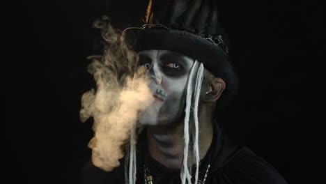 Creepy-man-with-skeleton-makeup.-Guy-exhaling-cigarette-smoking-from-his-mouth-and-smiling