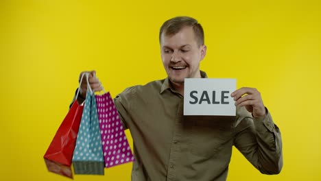 Happy-smiling-man-with-shopping-bags-showing-Black-Friday-inscription-on-bags-and-Sale-word-note