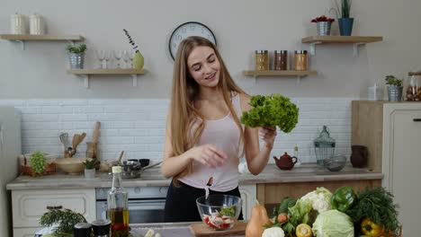 Young-girl-dancing,-having-fun-and-cooking-salad-with-raw-vegetables.-Throwing-pieces-of-lettuce