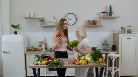 Mature-woman-with-grandchild-girl-recommending-eating-raw-vegetable-food.-World-vegan-day-concept
