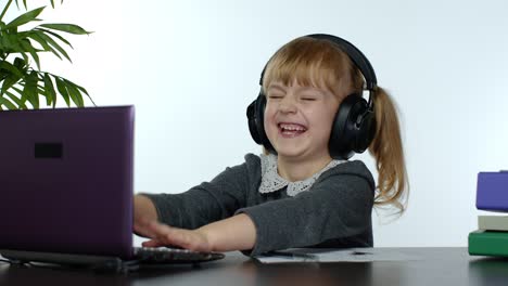 Child-schoolgirl-kid-laughing-and-smiling.-Learning-lessons-at-home-and-using-laptop-computer