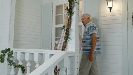 Senior-elderly-couple-drinking-coffee,-looking-ahead-in-porch-at-home.-Mature-family-in-own-house