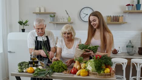 Senior-couple-in-kitchen-receiving-vegetables-from-granddaughter.-Healthy-raw-food-nutrition