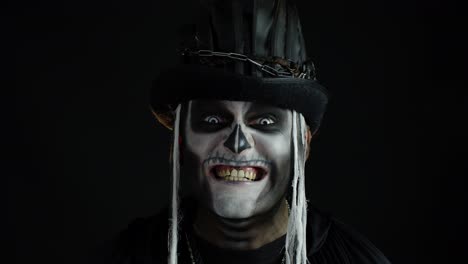 Man-with-skeleton-makeup-trying-to-scare,-opening-his-mouth-and-showing-dirty-black-teeth-and-tongue