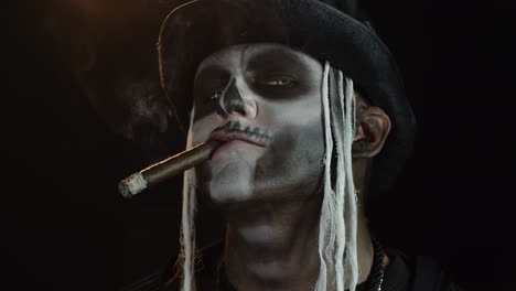 Scary-guy-in-professional-carnival-makeup-of-Halloween-skeleton-smoking-cigar,-making-faces,-smiling