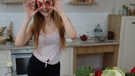 Joyful-young-girl-vegan-dancing-holding-fresh-red-slice-of-bell-pepper-on-eyes.-Healthy-nutrition