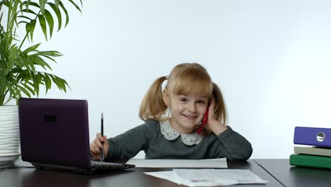 Funny-little-child-girl-boss-manager-emotionally-talking-on-mobile-phone,-sitting-at-computer-table
