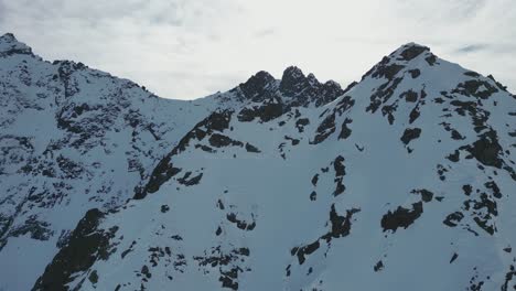 Steiler,-Schneebedeckter-Berggipfel-Aus-Der-Luft,-Der-An-Einem-Sonnigen-Tag-In-Richtung-Des-Schneebedeckten-Gipfels-Fliegt,-Alpine-Landschaft