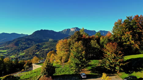 Vista-De-Drones-Que-Se-Eleva-Desde-El-Estacionamiento-Sobre-Los-árboles-Para-Revelar-Una-Vista-Impresionante-De-Las-Montañas-En-Austria