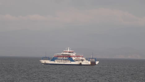 White-and-blue-ferry-boat-transporting-passengers,-cargo,-and-vehicles,-across-the-Pacific-Ocean-on-a-sunny-day-in-the-Gulf-of-Nicoya,-Costa-Rica