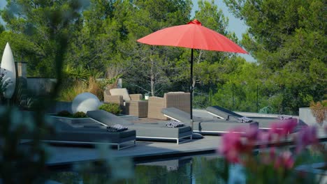 Scenic-poolside-with-sunbeds-and-an-ubrella-in-the-sunny-garden-of-a-french-villa