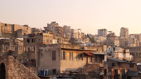 Schwenkaufnahme-Der-Dächer-Des-Nahen-Ostens-Im-Dunstigen-Sonnenuntergangshimmel-In-Tripolis,-Nordlibanon