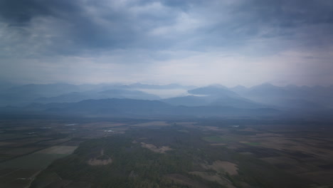 Aerial-timelapse-over-empty-fields-in-Georgia-with-the-Caucasus-Mountains-and-clouds-in-the-background