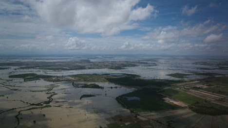 Lufthyperlapse-Von-Tageswolken,-Die-über-Die-überfluteten-Reisfelder-Im-Ländlichen-Kambodscha-Fliegen