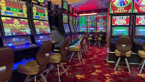 Casino-floor-with-slot-machines-and-chairs,-colorful-flashing-lights,-static-view