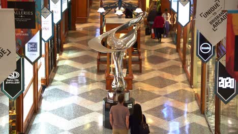 Tourists-and-shoppers-shopping-at-iconic-Brisbane-arcade,-shopping-galleria-in-heritage-listed-building-with-Mirage-sculpture-by-Gidon-Graetz-as-the-centrepiece-at-Queen-Street-Mall,-Brisbane-city