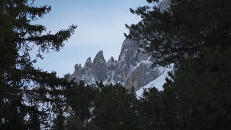 Toma-De-Paralaje-De-La-Cima-De-Una-Montaña-Alpina-Cubierta-De-Nieve-Enmarcada-Por-árboles-Oscuros