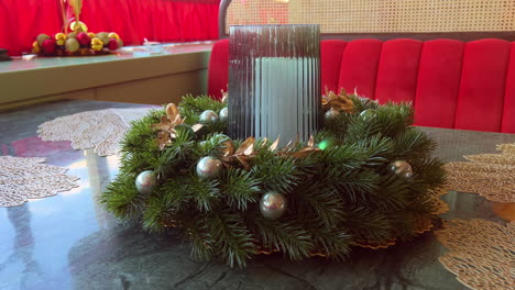 Christmas-wreath-with-candle-in-glass-holder-placed-on-table-in-pastry-shop