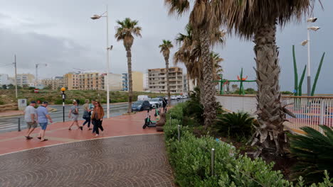 Gente-Caminando-Por-Una-Calle-Con-Palmeras-En-La-Valeta,-Malta-Durante-El-Día
