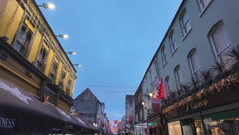 Christmastime-on-the-street-in-Cork-city-with-shops-and-people,-Ireland