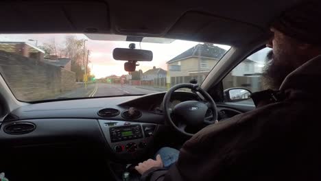 POV-bearded-man-driving-through-British-suburban-town-streets-and-traffic-view-from-interior-vehicle-perspective