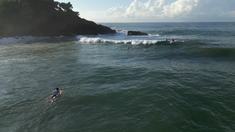 Pullback-Luftdrohnenaufnahme-Eines-Männlichen-Surfers,-Der-Auf-Einem-Surfbrett-Sitzt-Und-Auf-Einer-Welle-In-Richtung-Meer-Im-Süden-Sri-Lankas-Reitet