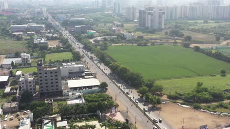 Rajkot-city-aerial-view-drone-camera-where-high-rise-building-work-is-going-on,-and-on-the-right-is-a-large-farm