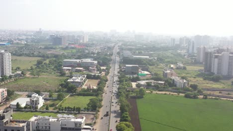 Rajkot-city-aerial-view-Drone-is-flying-in-the-middle-of-Kalavad-road,-a-temple-is-also-visible-on-the-side-of-the-road