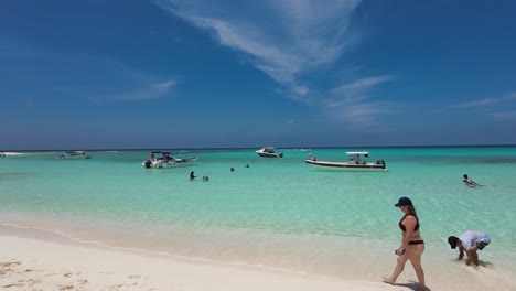 Cayo-de-Agua-island-Beach-with-people-enjoy-summer-time,-turquoise-sea-water,-pan-right