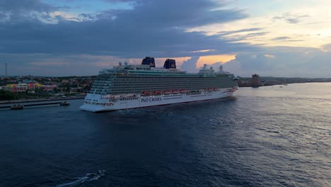 Wide-angle-trucking-pan-ascend-reveals-skiff-and-cruise-ship-docked-at-Caribbean-port